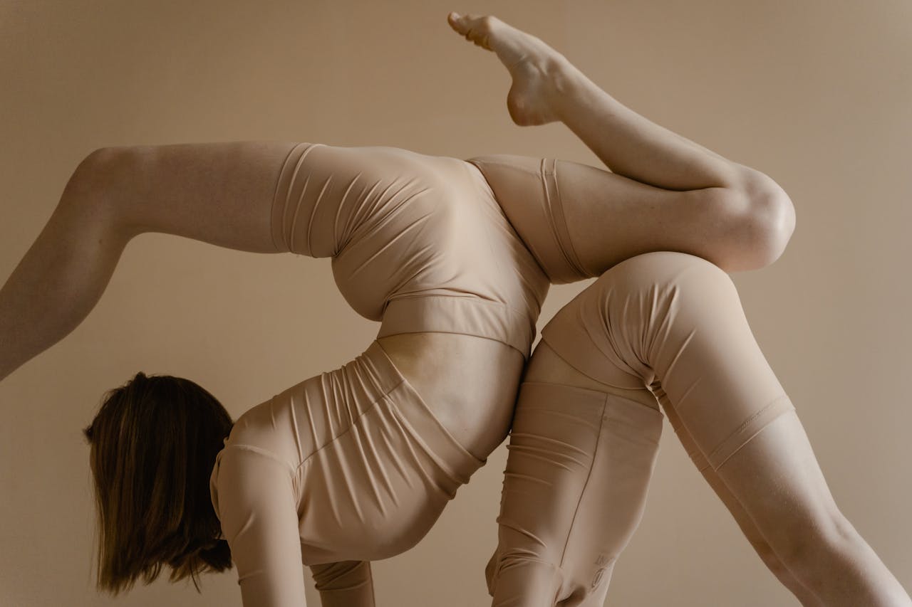 Two young women performing an intricate dance pose, showcasing flexibility.